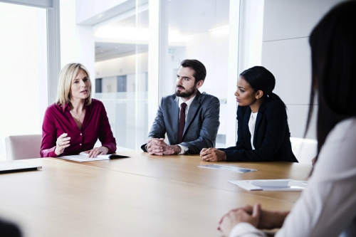 Mature female business professional talking to colleagues in boardroom. Businesswoman speaking to executives in company meeting. Group of modern business people